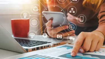Une personne utilise un smartphone et un ordinateur portable avec des graphiques sur une table.