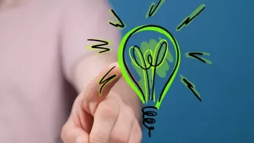 Main tendant un dessin d'ampoule lumineuse verte