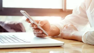 Personne utilisant un smartphone près d'un ordinateur portable.