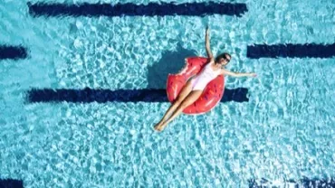 Personne flottant sur une bouée en forme de donut dans une piscine.