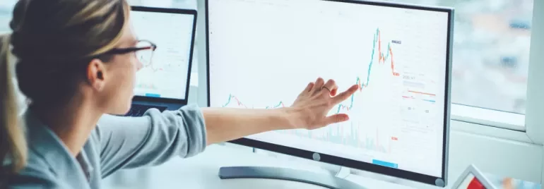 Personne pointant un graphique sur un écran d'ordinateur.
