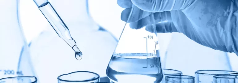 Main portant un flacon avec liquide, pipette transférant une goutte.