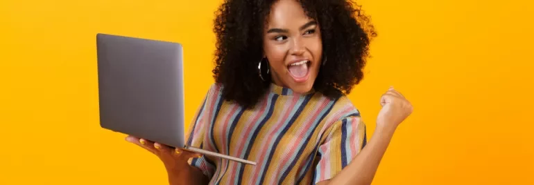 Personne souriante tenant un ordinateur portable sur fond jaune.