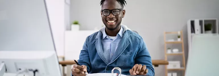 Personne souriante travaillant à un bureau avec des documents.