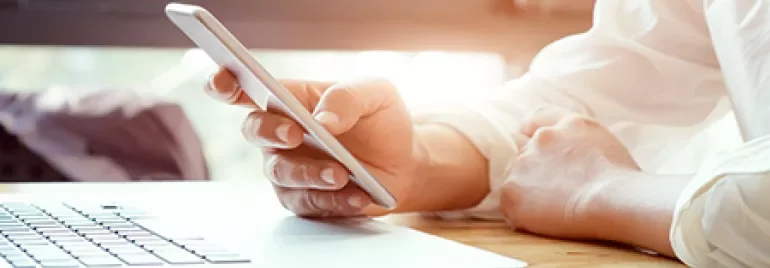 Personne utilisant un smartphone près d'un ordinateur portable.
