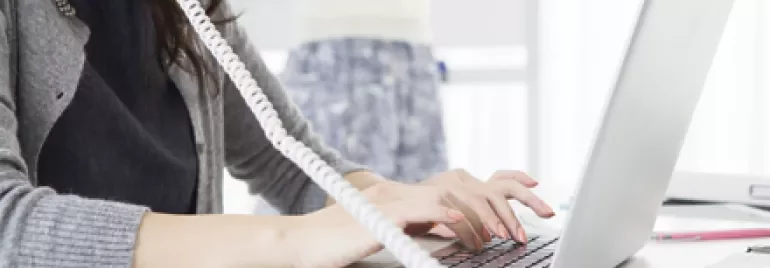 Personne utilisant un ordinateur portable et parlant au téléphone.
