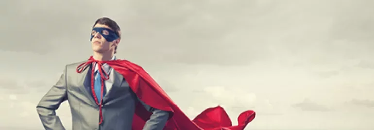 Homme en costume avec cape rouge et masque, debout sur un toit.