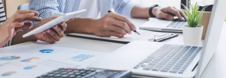 Personnes travaillant sur des ordinateurs portables avec une calculatrice et des graphiques.