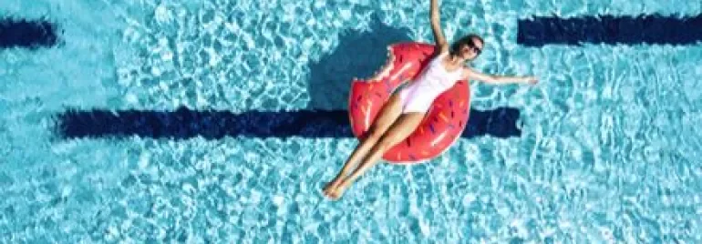 Personne flottant sur une bouée en forme de donut dans une piscine.