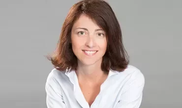 Portrait d'une personne souriante en chemise blanche.